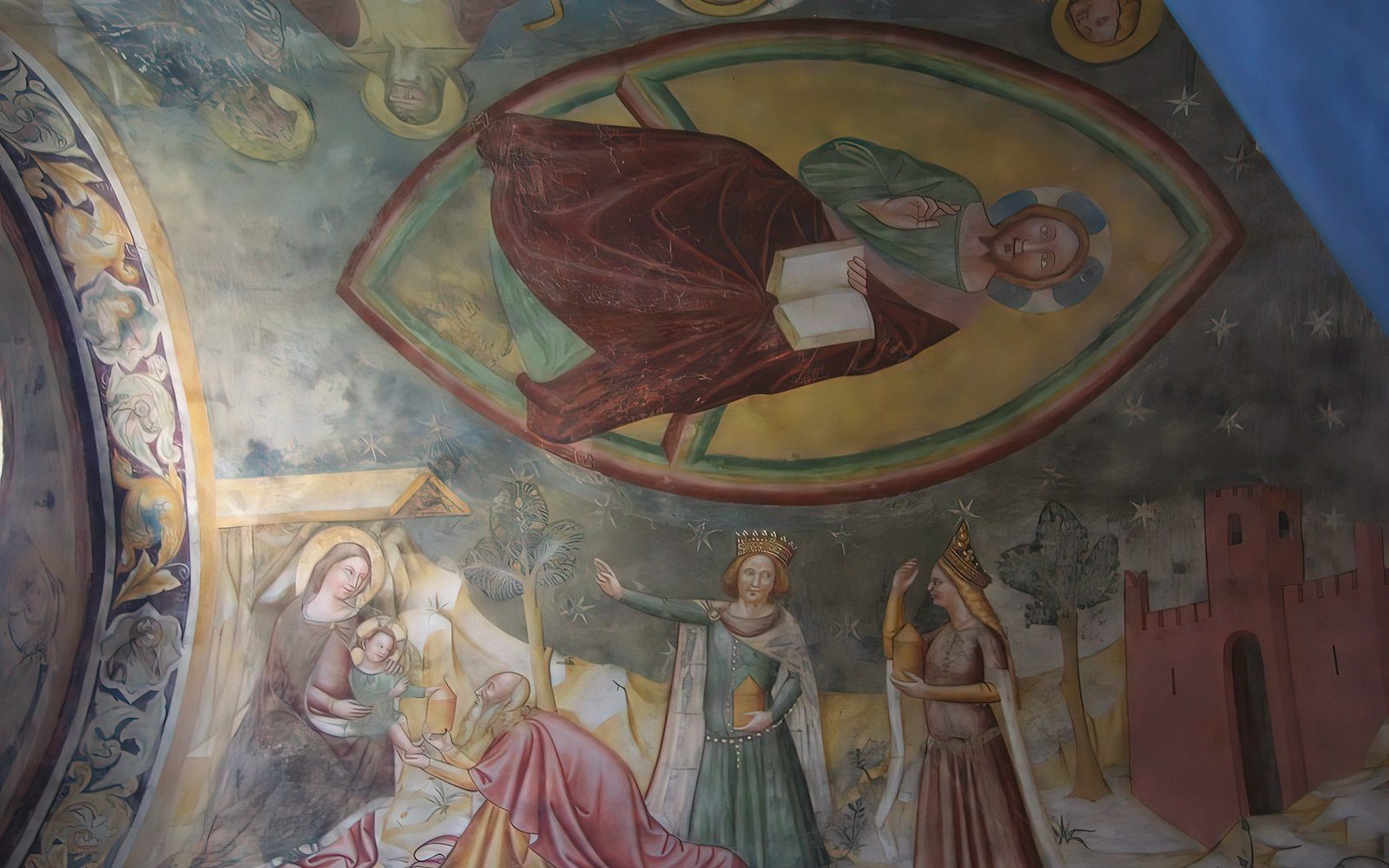 Ceiling fresco of a haloed saint holding a book above a nativity and adoration scene